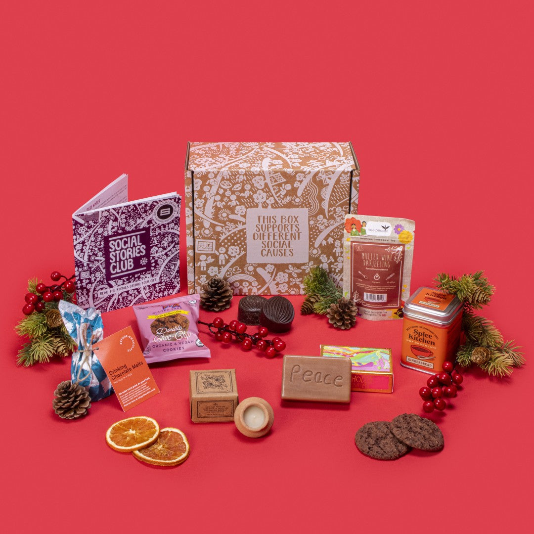 Cosy Winter Warmer Gift Box open, showcasing mulled wine tea, chocolate chip cookies, organic soap, gingerbread hot chocolate, lavender candle, and hot chocolate melts with festive pine cones and red accents.