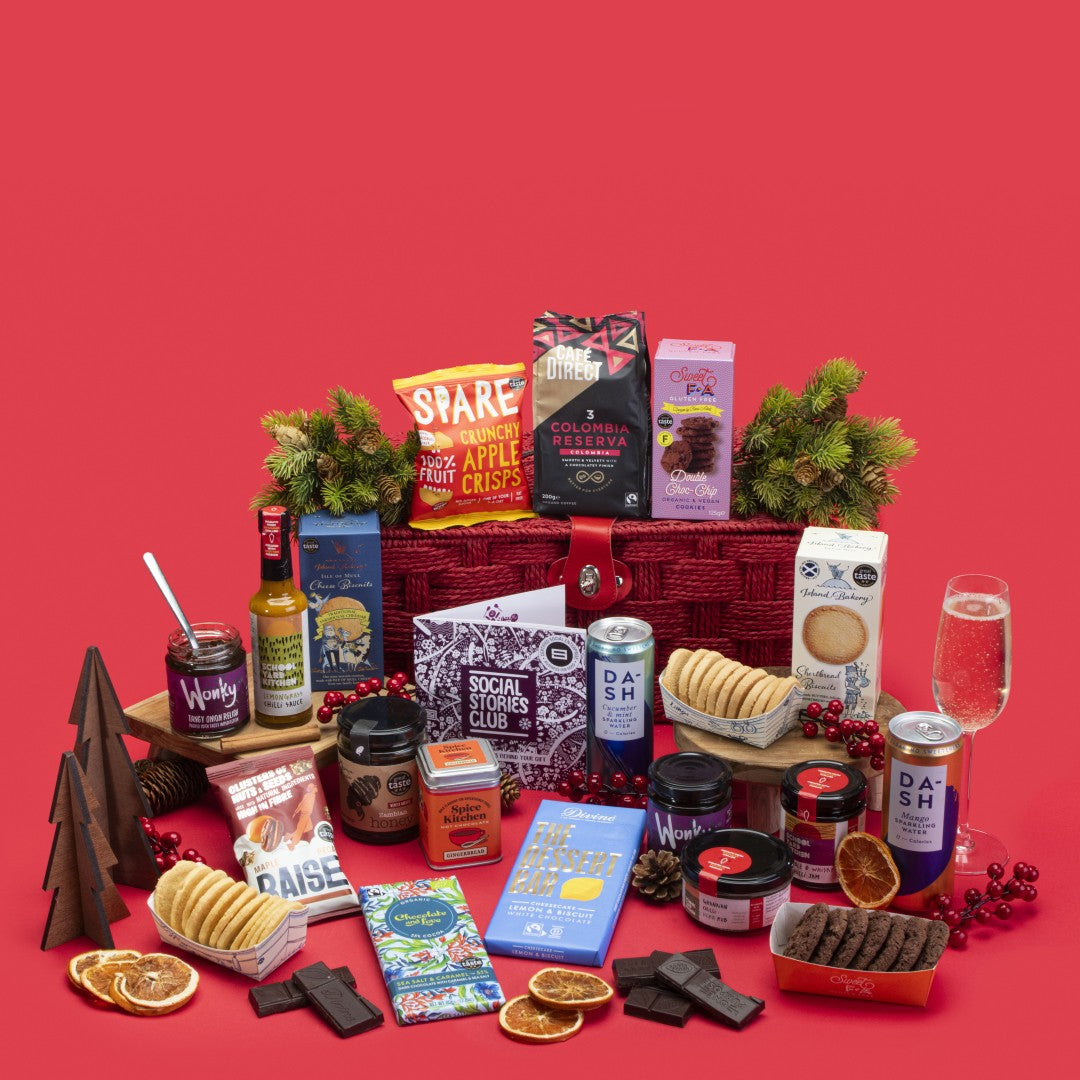 Traditional Food and Drink Gift Hamper open, showcasing Colombian coffee, shortbread and cheese biscuits, chocolate chip cookies, sea salt caramel chocolate, lemon cheesecake bar, gingerbread hot chocolate, apple crisps, tomato onion relishes, chilli jam sauce and rub, maple pecans, honey, mango and cucumber sparkling waters, story booklet, and personalised note in classic sustainable packaging with festive warmth.