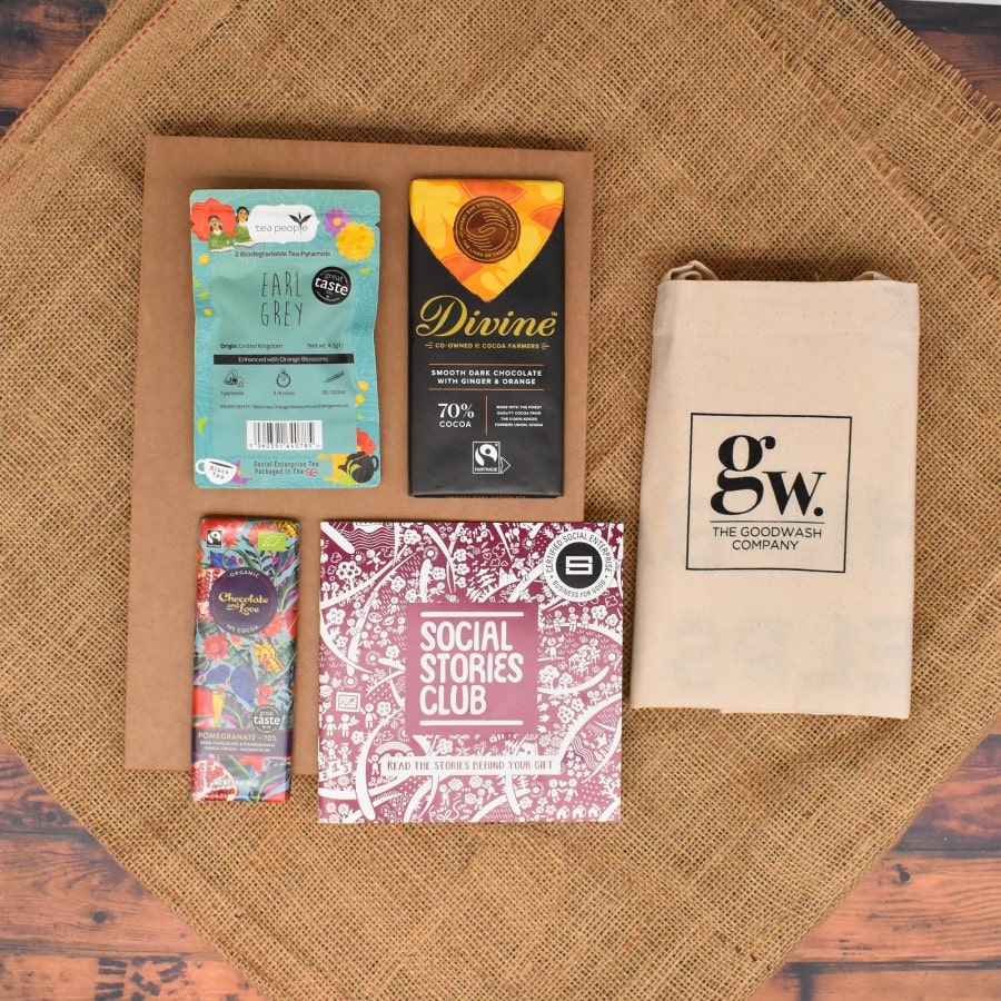 Letterbox Impact Gift open, displaying twin-pack Earl Grey tea, ginger orange dark chocolate, napolitain, natural cotton tote bag, story booklet & personalised note in compact sustainable packaging with festive accents.