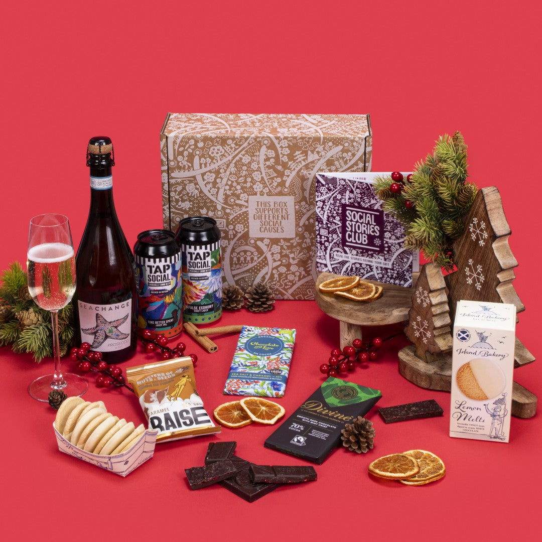 Celebration Gift Box open, featuring lemon melt biscuits, salted caramel and mint crisp chocolates, salted caramel nuts, choice of wine, craft lager, IPA, story booklet, and personalised note in vibrant sustainable packaging with wintery festive accents.