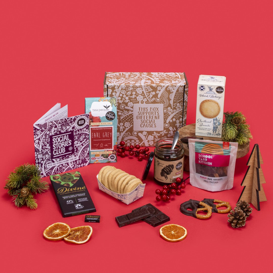 Client Appreciation Gift Box open, displaying Earl Grey tea, shortbread biscuits, dark chocolate napolitain and hazelnut truffle, chilli pretzels, pure honey, story booklet, and personalised note in refined sustainable packaging with cosy festive accents.