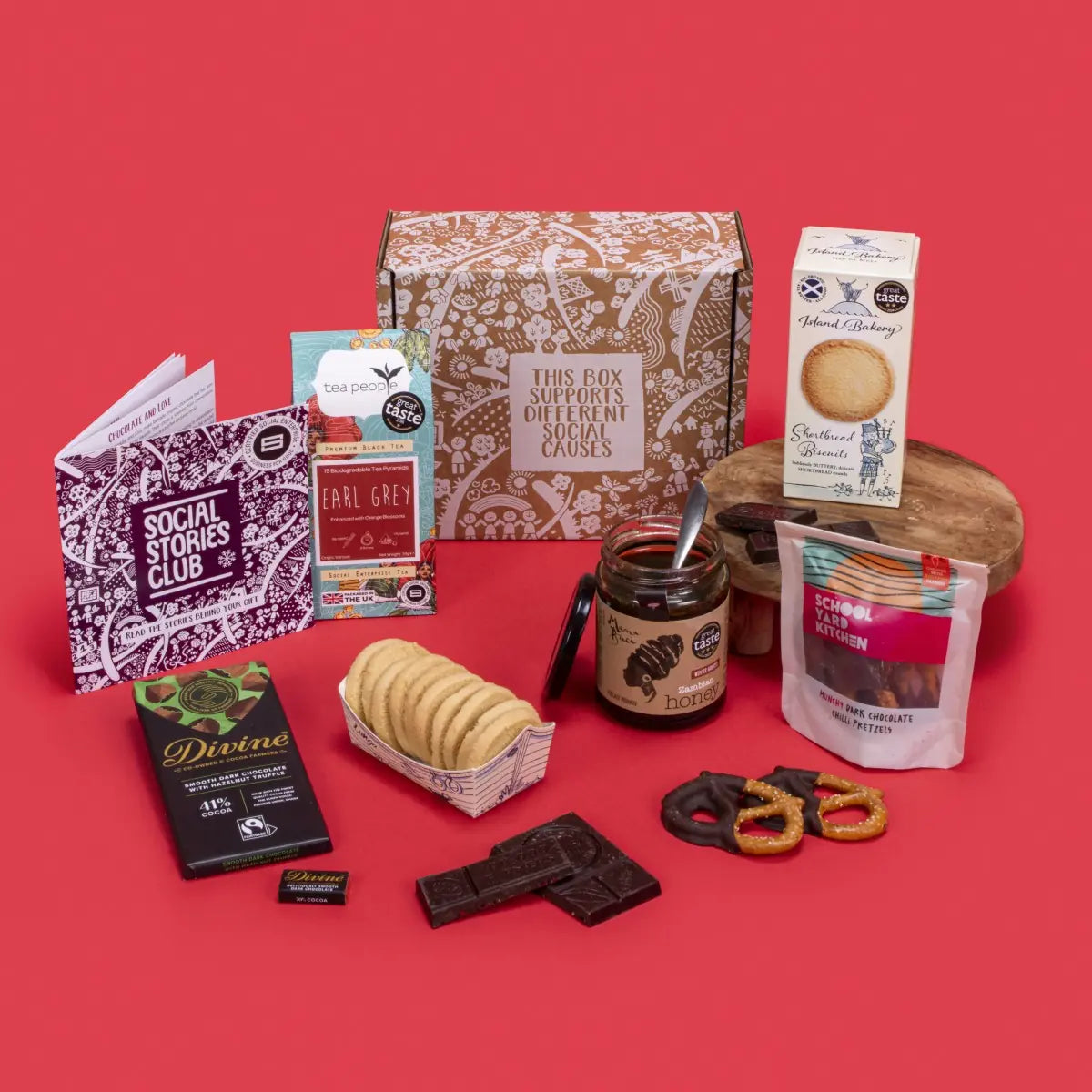 Client Appreciation Gift Box open, displaying Earl Grey tea, shortbread biscuits, dark chocolate napolitain and hazelnut truffle, chilli pretzels, pure honey, story booklet, and personalised note in refined sustainable packaging with cosy festive accents.