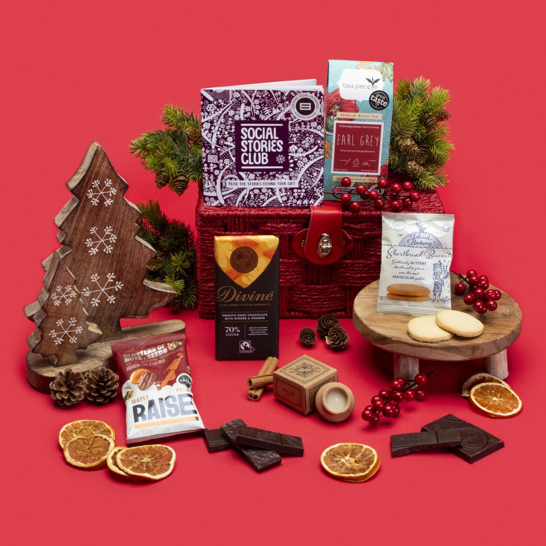 Social Impact Gift Hamper open, displaying Earl Grey tea, twin-pack shortbread, ginger orange dark chocolate, lavender candle, maple pecan nuts, story booklet & personalised note in luxurious sustainable packaging with festive accents.