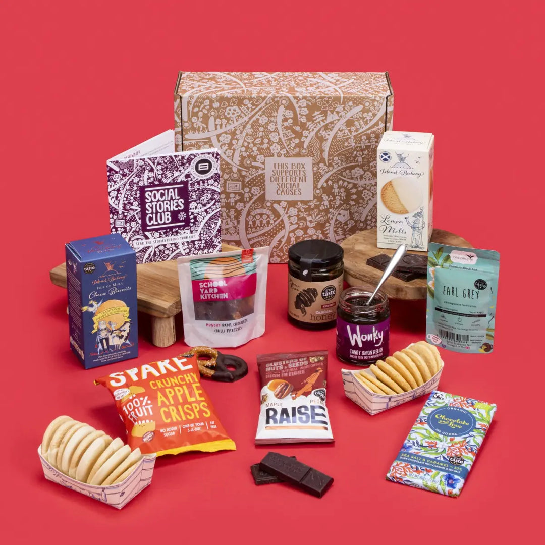 Sustainable Foodie Gift Box open, displaying Earl Grey tea twin-pack, lemon melt biscuits, cheese biscuits, sea salt caramel chocolate, apple crisps, fiery tomato relish, chilli pretzels, maple pecans, honey, story booklet & personalised note in gourmet sustainable packaging with festive accents.