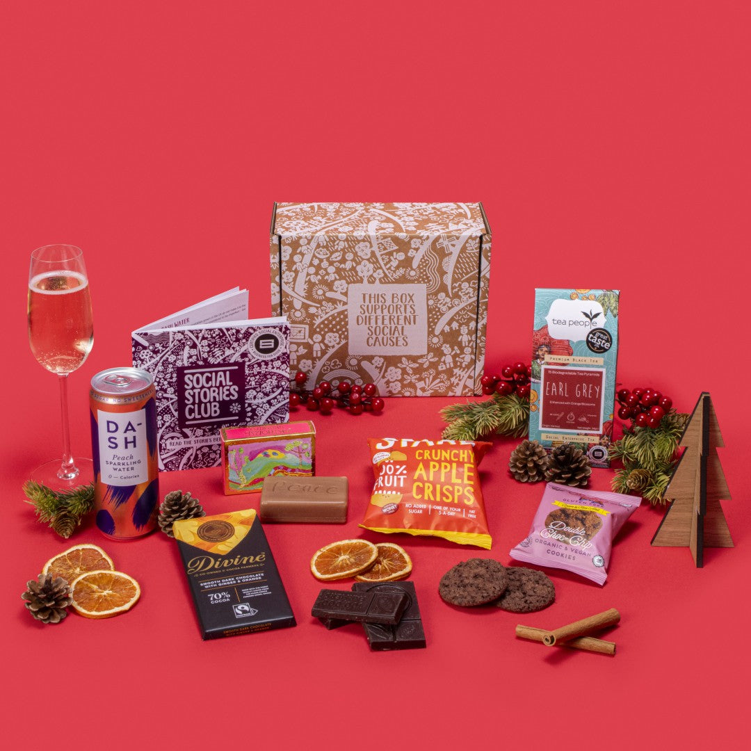Vegan Treats Gift Box open, displaying Earl Grey tea, double chocolate chip cookies twin-pack, ginger orange dark chocolate, apple crisps, peach sparkling water, rosemary orange exfoliating soap, story booklet & personalised note in fresh sustainable packaging with festive accents.