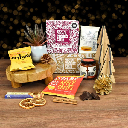 Winter Gift Box featuring sustainable treats like shortbread biscuits, sea salt & caramel chocolate, and apple crisps, each supporting a social cause.